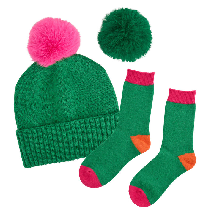 Green beanie with pink pom-pom and matching socks on a white background