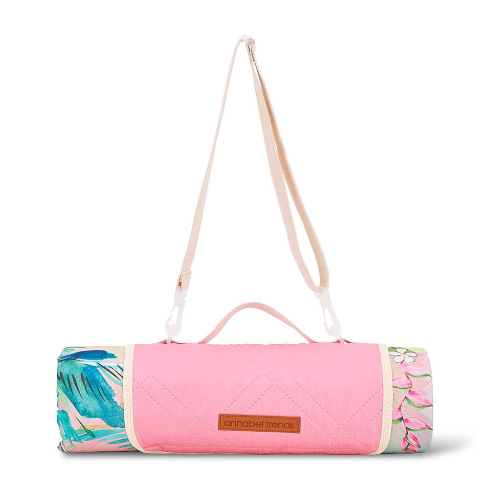 Rolled up picnic mat with floral patterns and a carrying strap on a white background