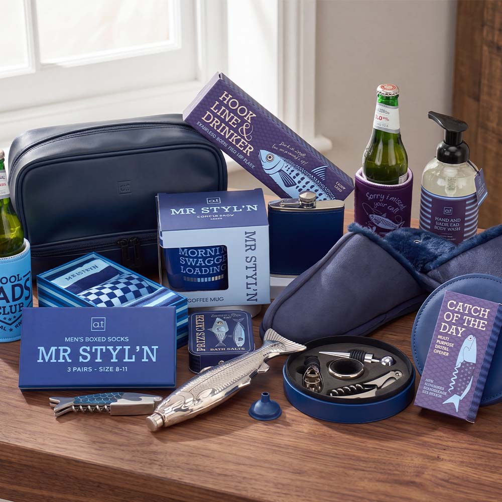 Collection of men's grooming and lifestyle products on a wooden surface with a window in the background.