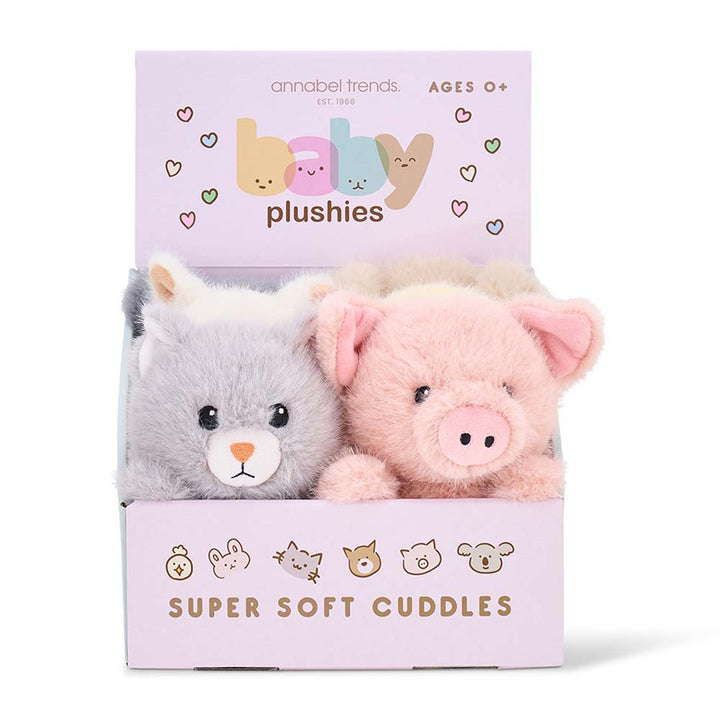 Two plush toys, a gray cat and a pink pig, in a box with 'annabel Trends' branding on a white background.