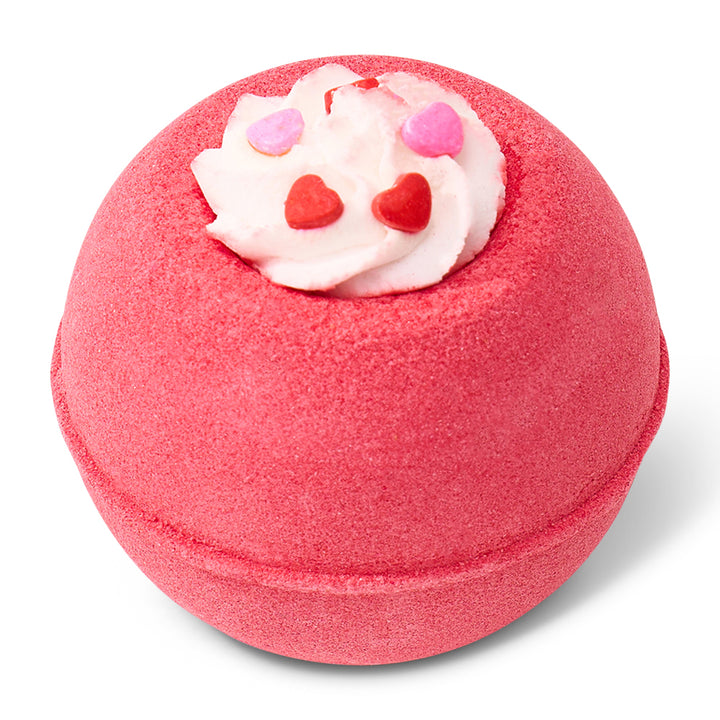 Pink bath bomb with white topping and red and pink hearts on a white background