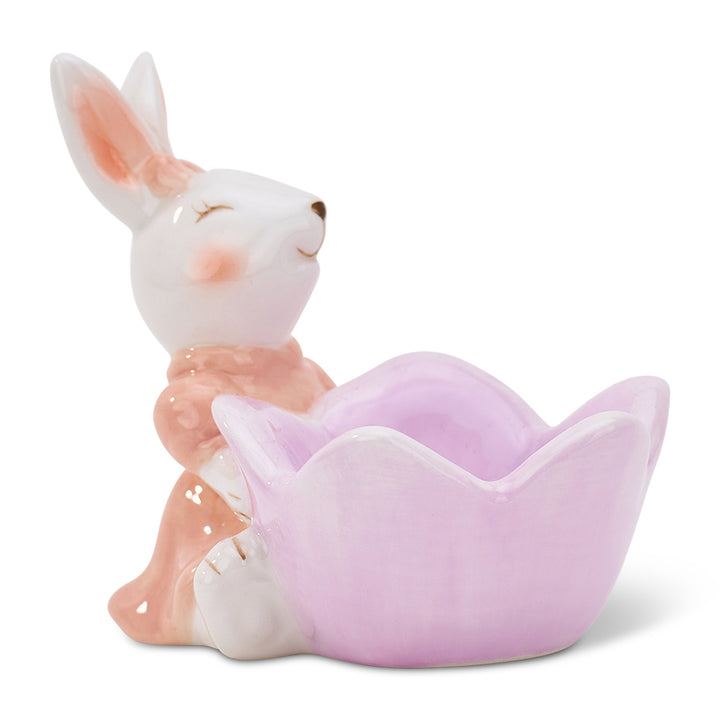 Ceramic rabbit egg cup sitting on a pink flower with a white background