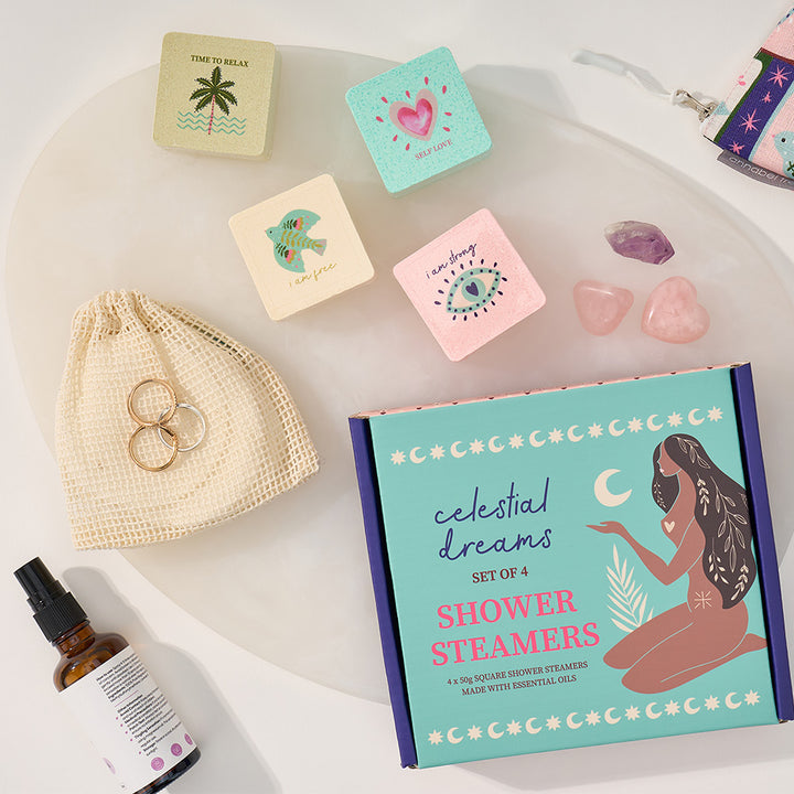 Set of celestial-themed shower steamers with decorative boxes and a drawstring bag on a white surface.