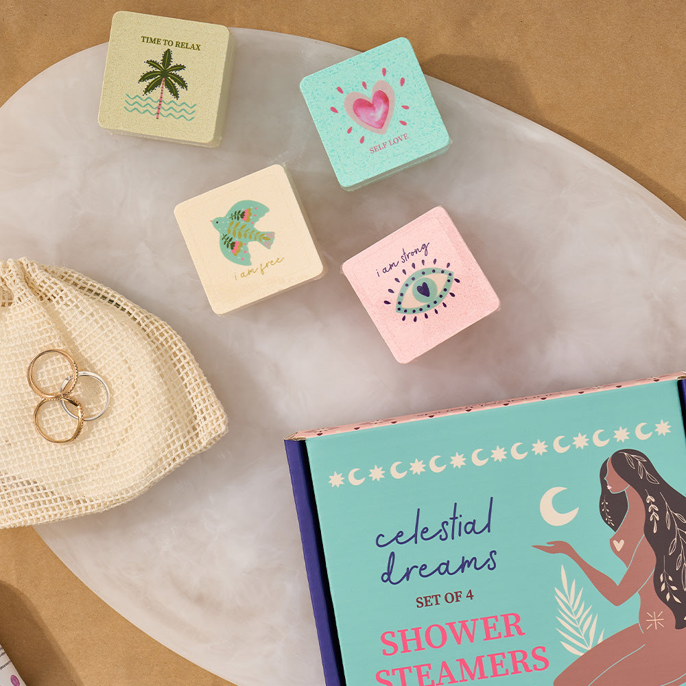 Set of four colorful shower steamers with a box labeled 'Celestial Dreams' on a marble surface.