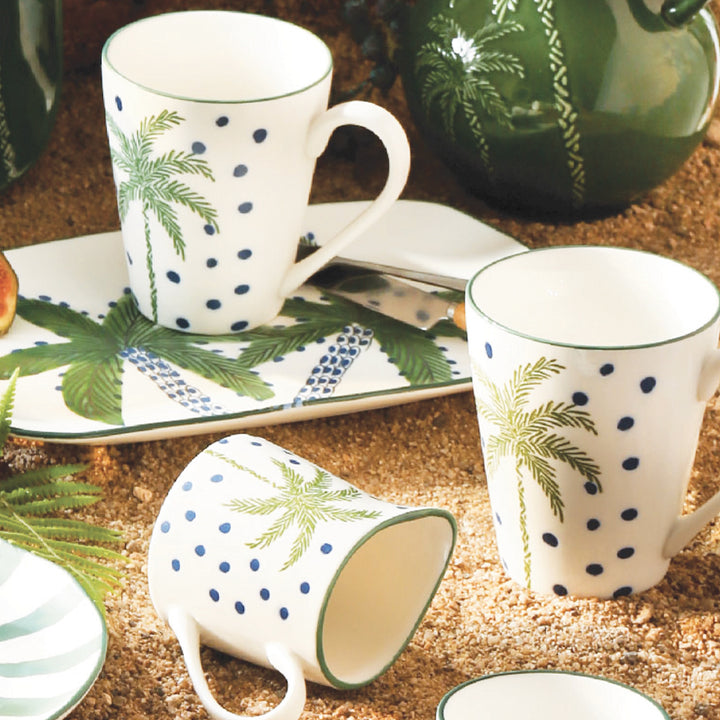 Set of ceramic mugs with leaf and dot patterns on a textured surface