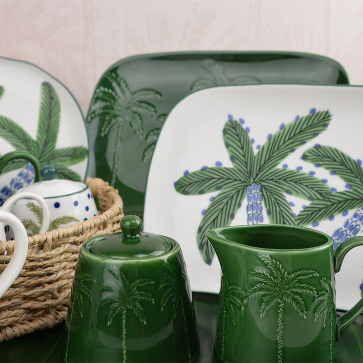 Green ceramic items with palm tree design on a neutral background