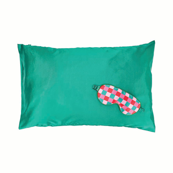 Green satin pillowcase with a pink and green checkered sleep mask on a white background