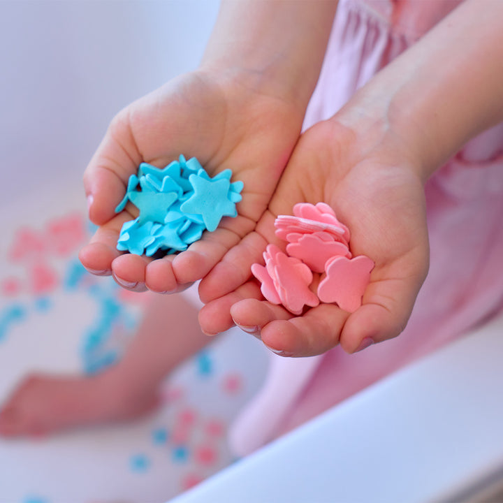 Children's hands holding blue and pink star-shaped objects against a blurred background