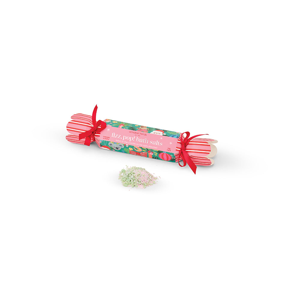 Roll of bath salts with floral design and red ribbon on a white background