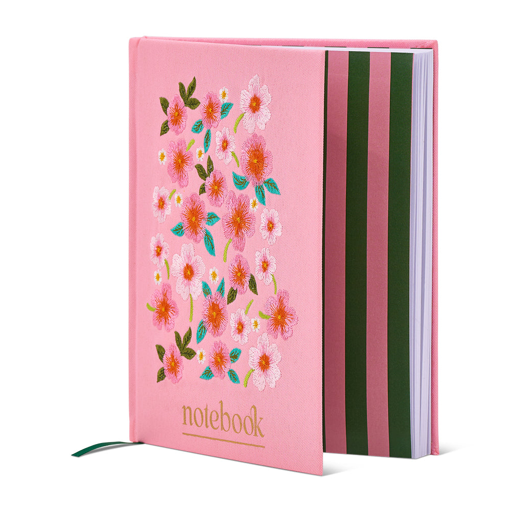 Pink notebook with floral design and striped back on a white background