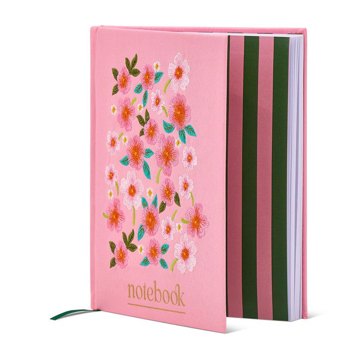 Pink notebook with floral design and striped back on a white background