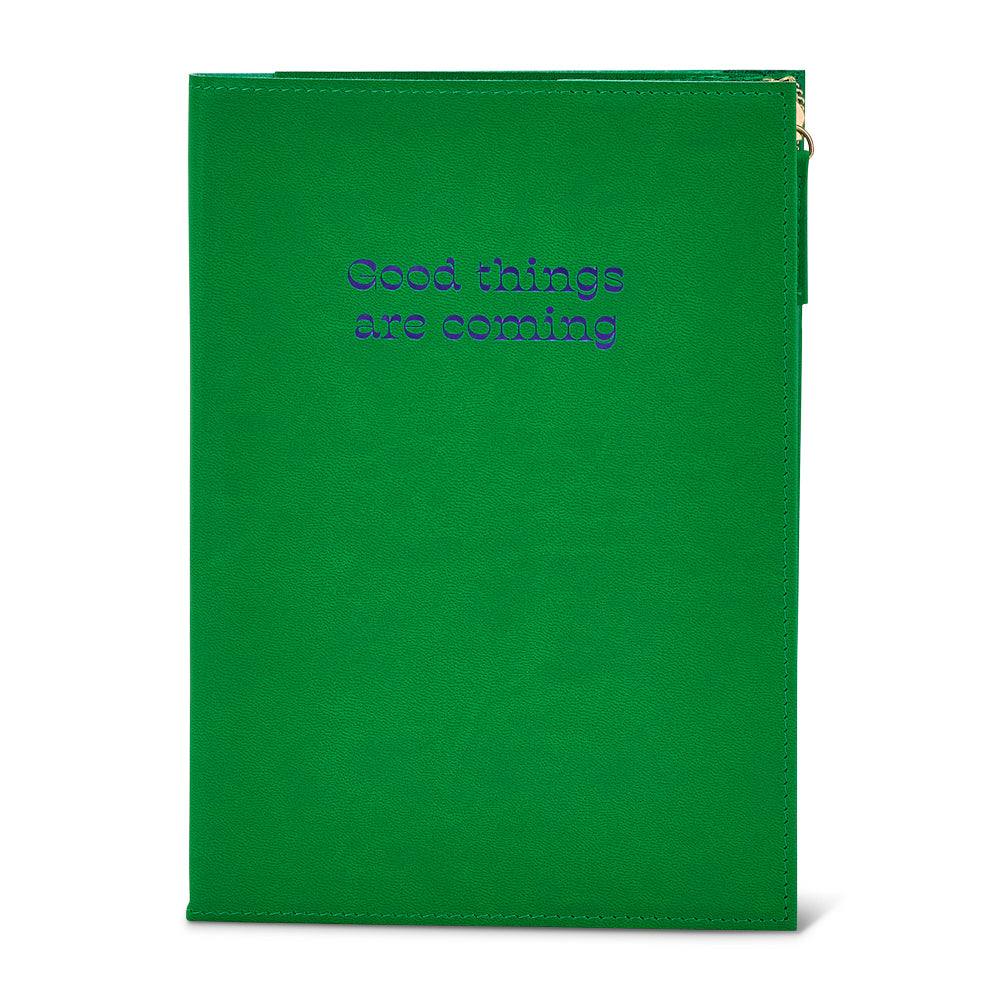 Green notebook with pouch with 'Good things are coming' text on a white background