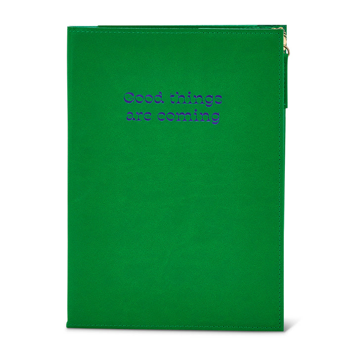 Green notebook with pouch with 'Good things are coming' text on a white background