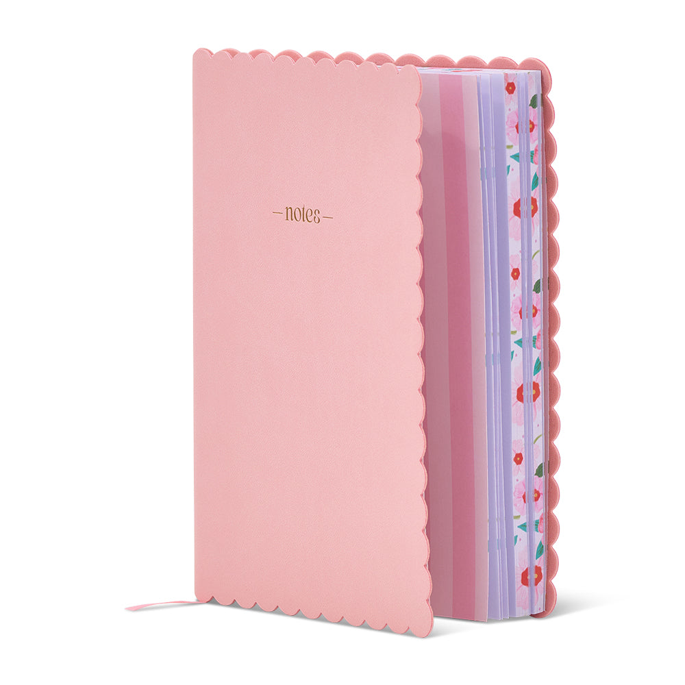 Pink notebook with scalloped edge and colorful ribbon on a white background