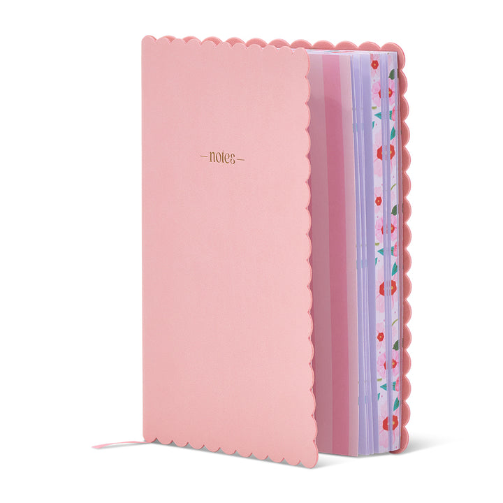 Pink notebook with scalloped edge and colorful ribbon on a white background