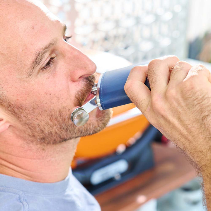 Man using a blue Hip flask device outdoors.