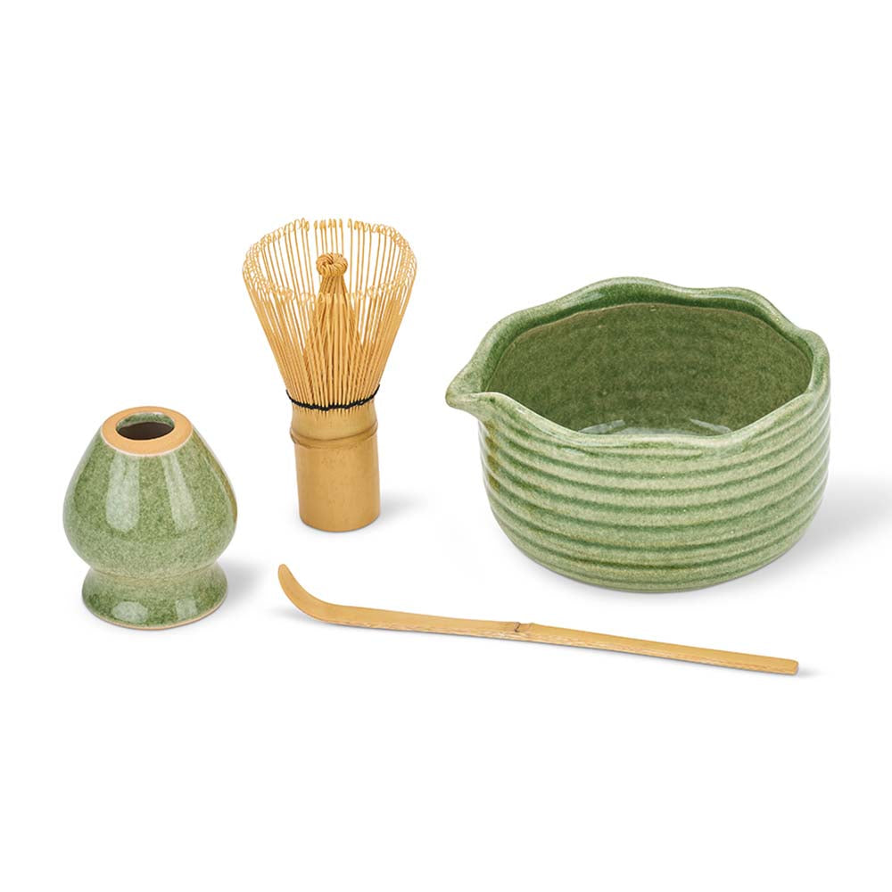 Set of green ceramic tea-making tools including a whisk, bowl, and spoon on a white background