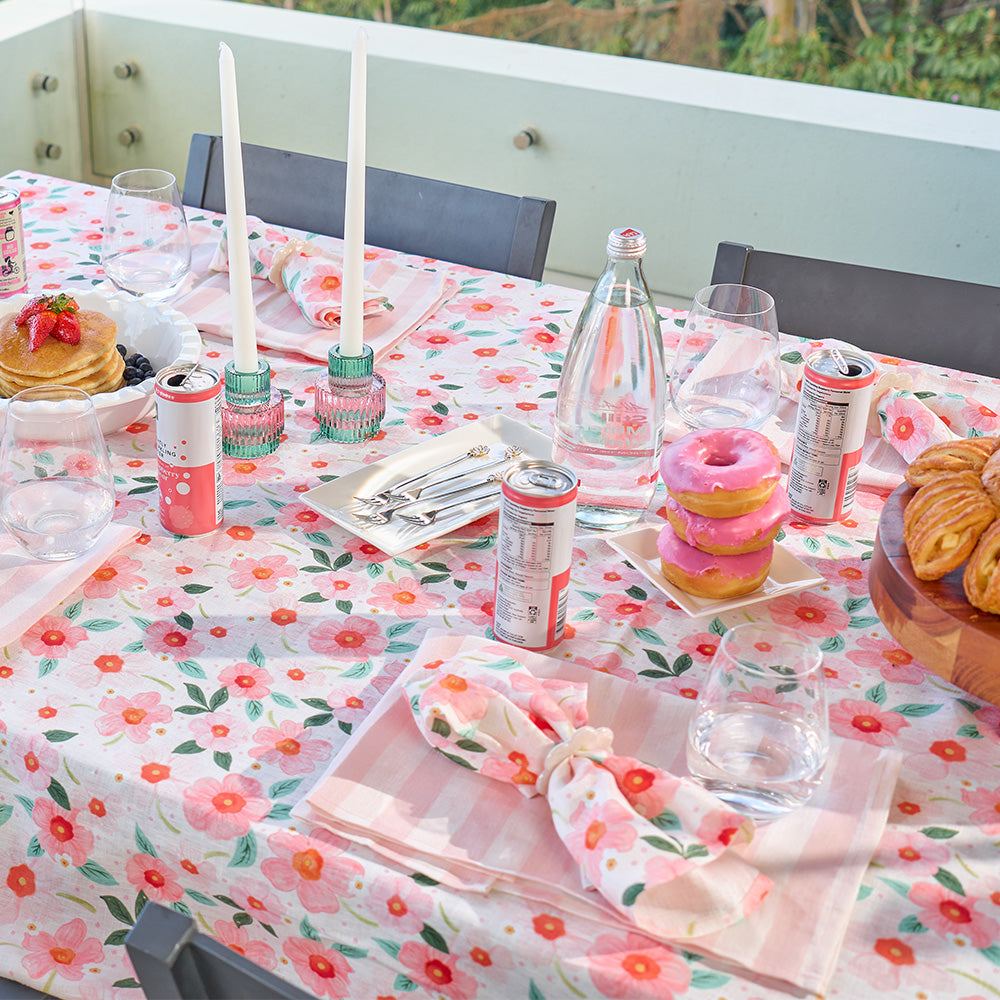 Outdoor table setting with a floral tablecloth, food, and drinks.