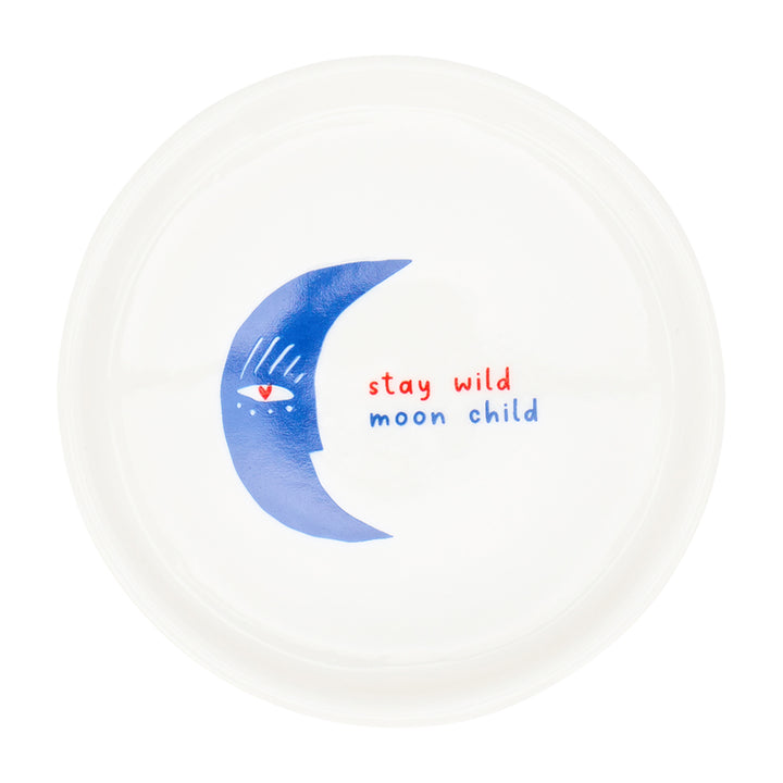 White plate with a blue crescent moon design and 'stay wild moon child' text on a white background