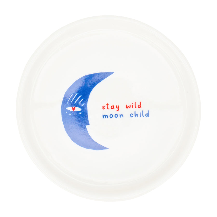 White plate with a blue crescent moon design and 'stay wild moon child' text on a white background