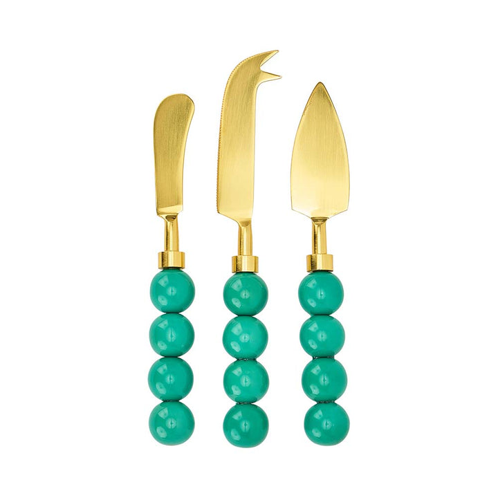 Three gold cheese knives with turquoise bead handles on a white background