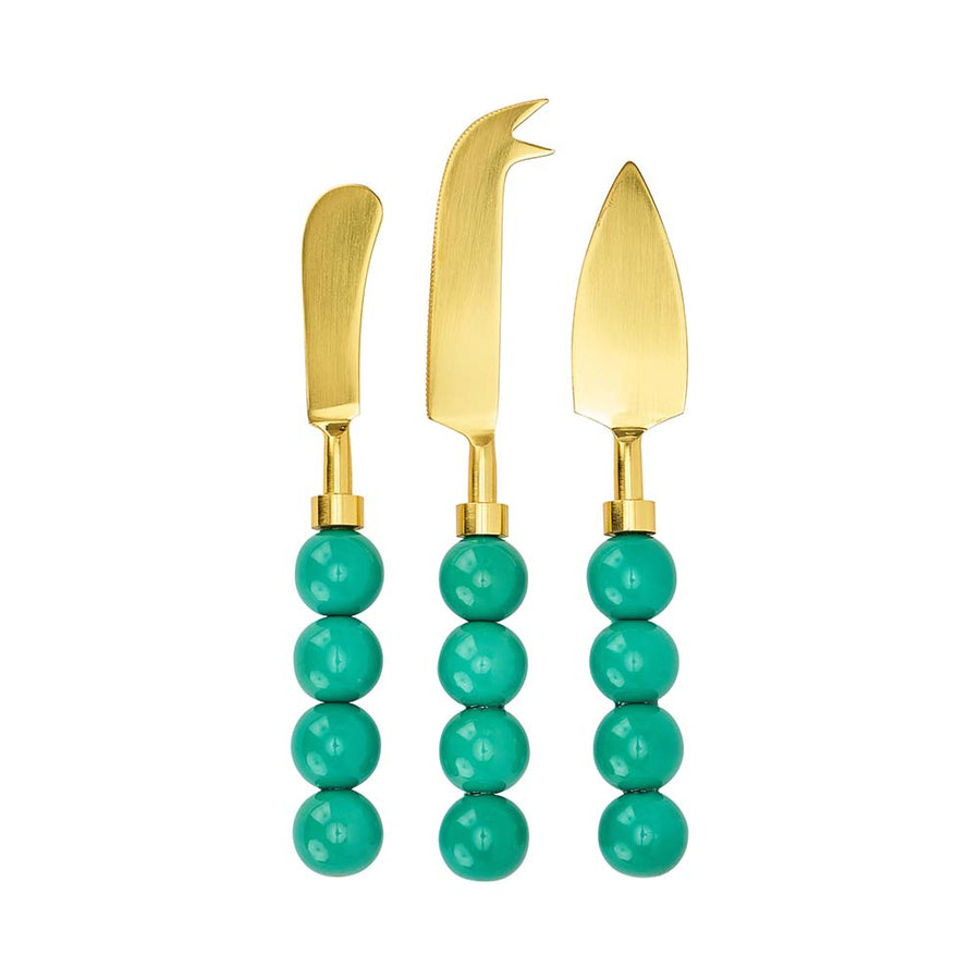 Three gold cheese knives with turquoise bead handles on a white background