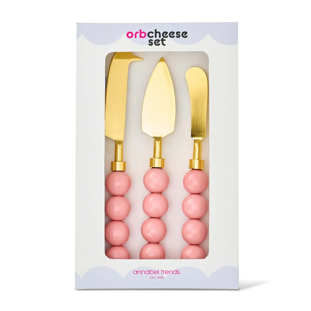 Three gold cheese knives with pink handles in a white box packaging, featuring 'orb cheese set' branding.