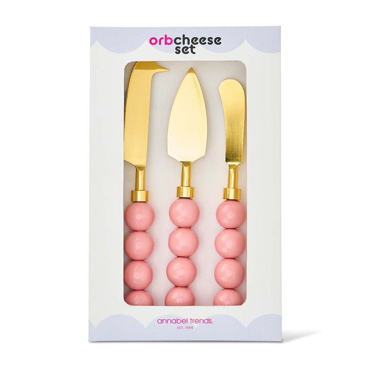 Three gold cheese knives with pink handles in a white box packaging, featuring 'orb cheese set' branding.