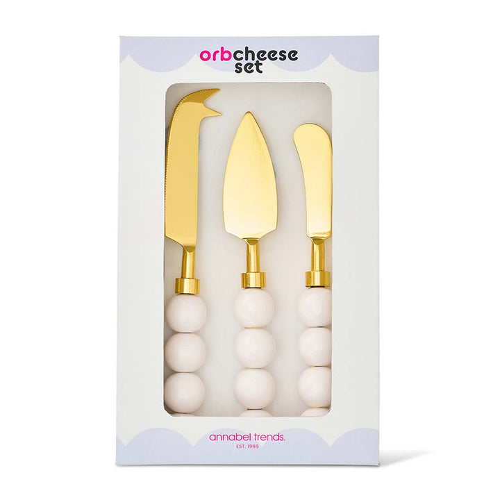 Set of three gold cheese knives with white handles in packaging, brand 'annabel Trends' visible.
