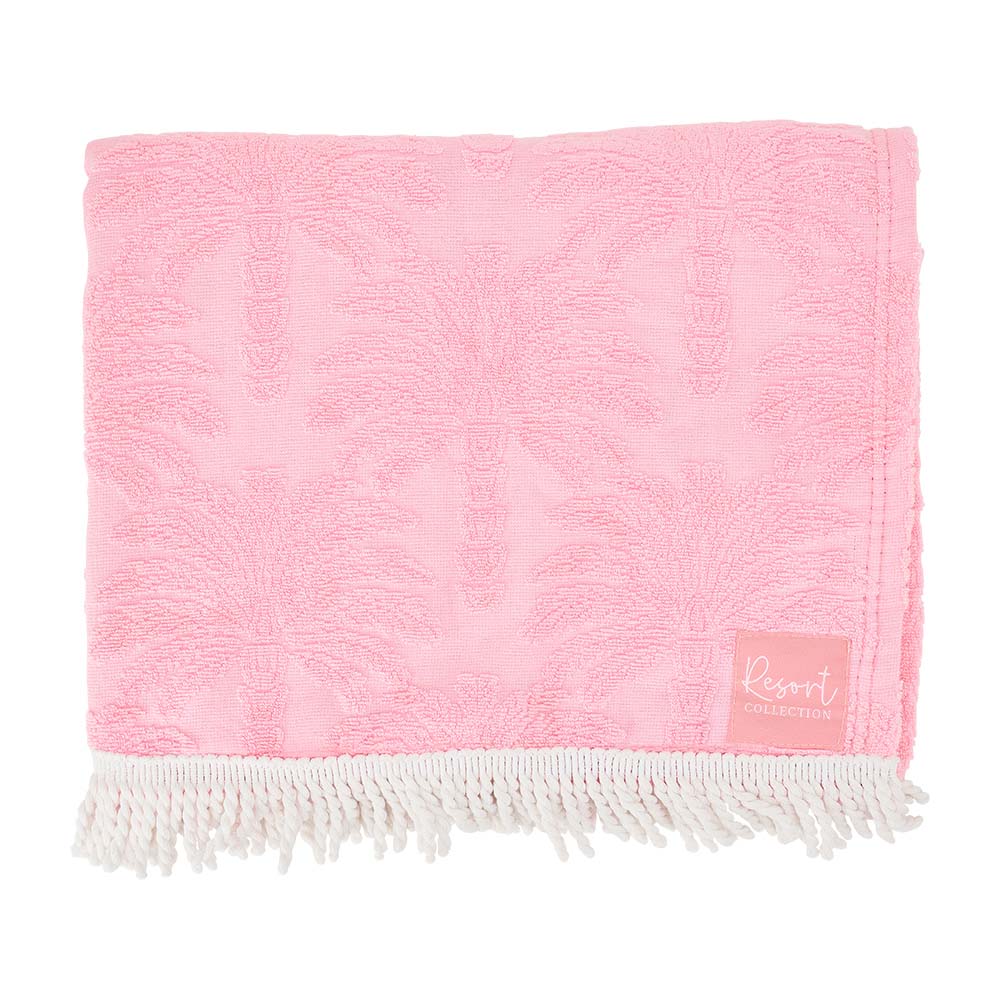 Pink towel with white fringe and a small label on a white background
