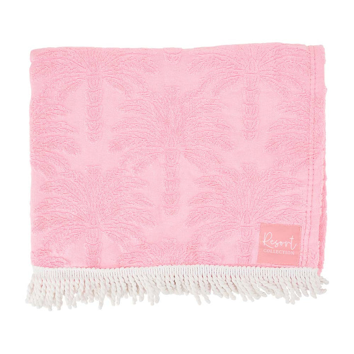 Pink towel with white fringe and a small label on a white background