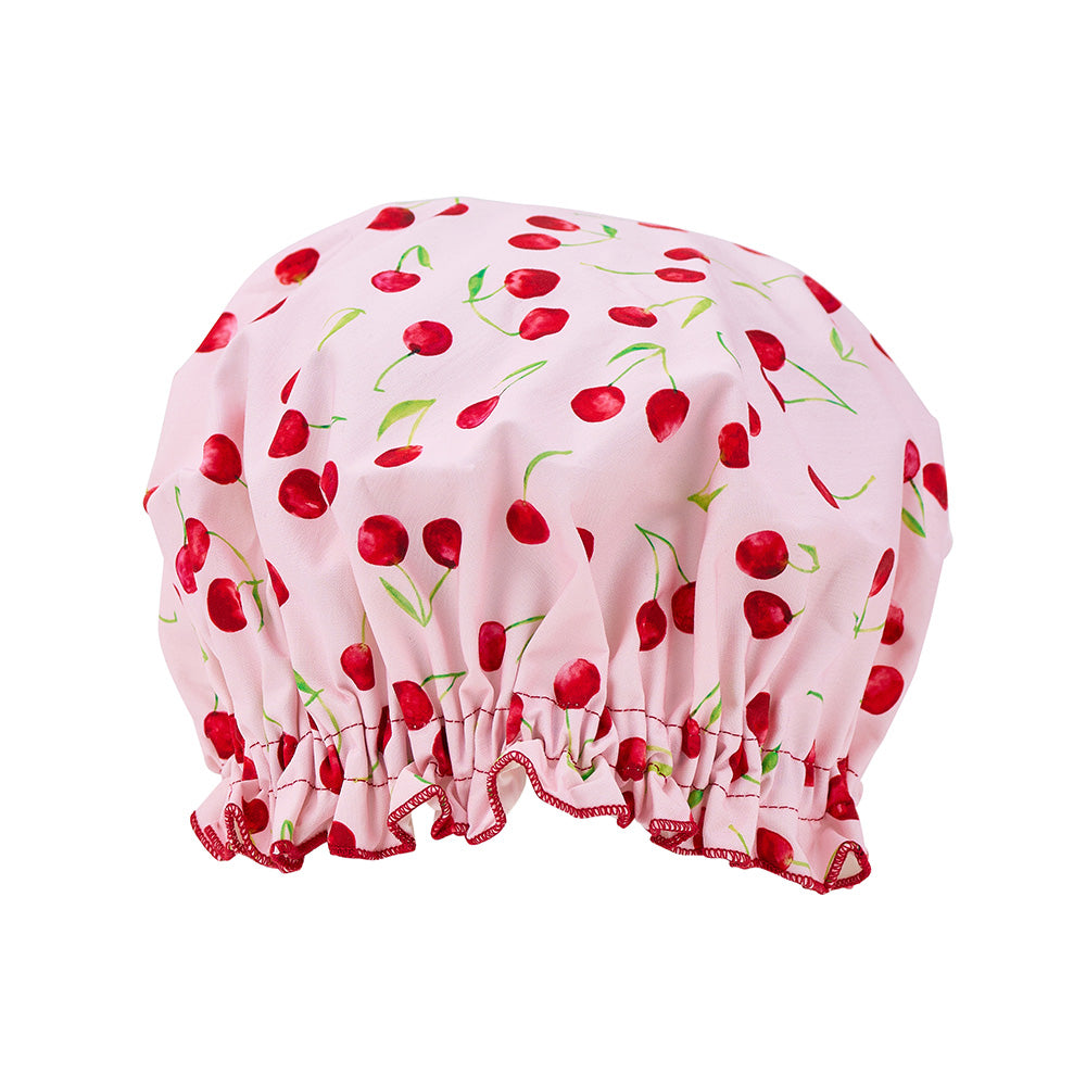 Pink shower cap with red cherry pattern on a white background