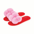 Red slippers with pink fuzzy pom-poms on a white background