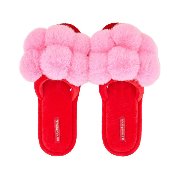 Red slippers with pink fuzzy pom-poms on a white background