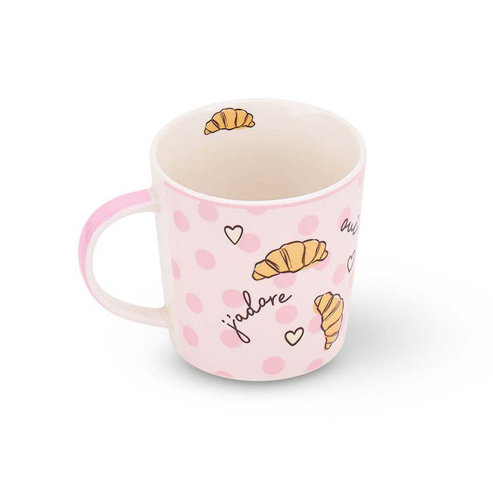 Pink mug with croissant and polka dot design on a white background