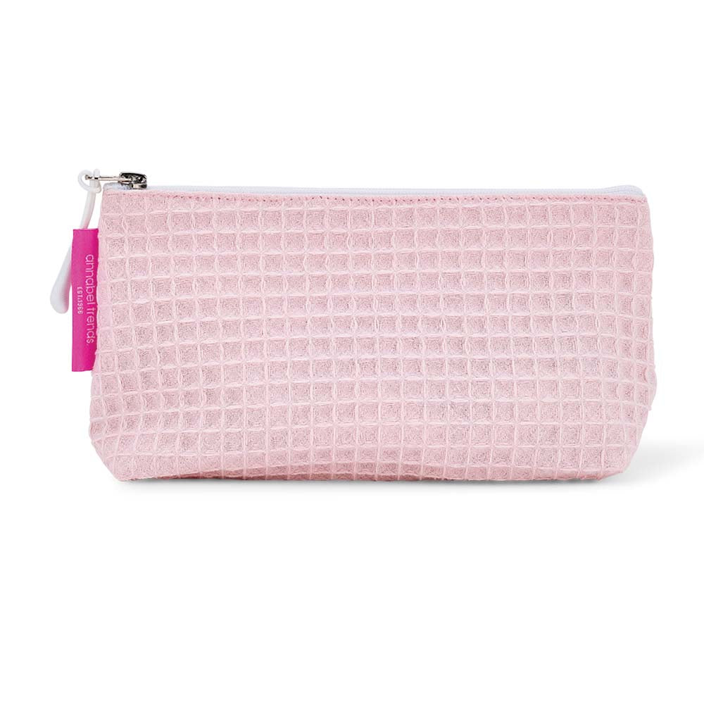 Pink waffle-textured cosmetic bag with a white zipper on a white background