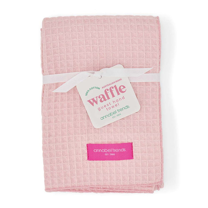 Pink waffle hand towel with a label on a white background