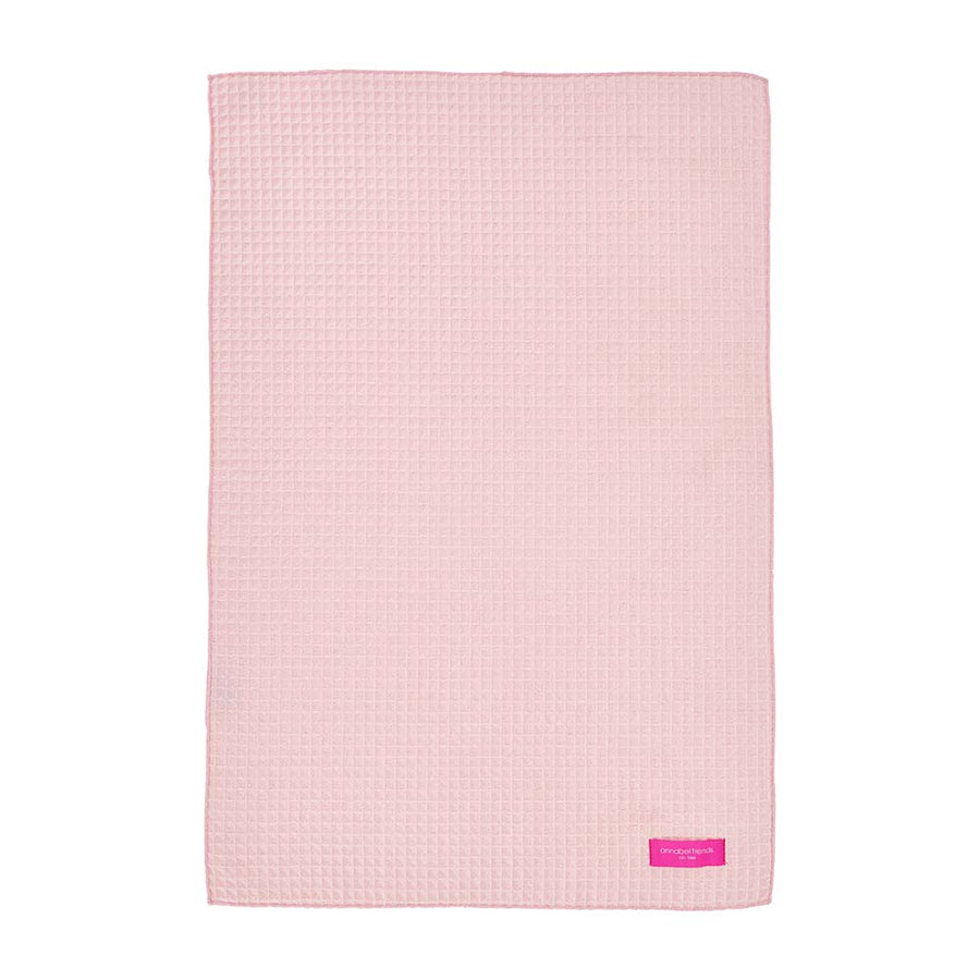 Pink textured hand towel with annabel trends label on a white background