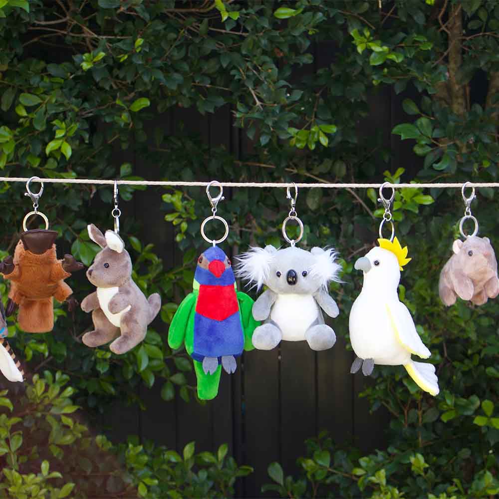 Plush animal keychains hanging on a line with a green foliage background