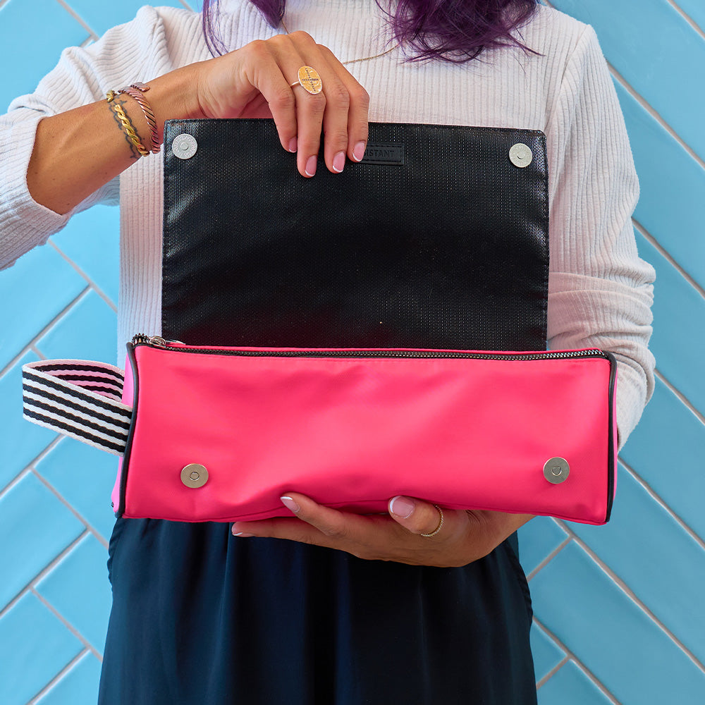 Person holding a pink and black hair straightener bag against a blue tiled wall