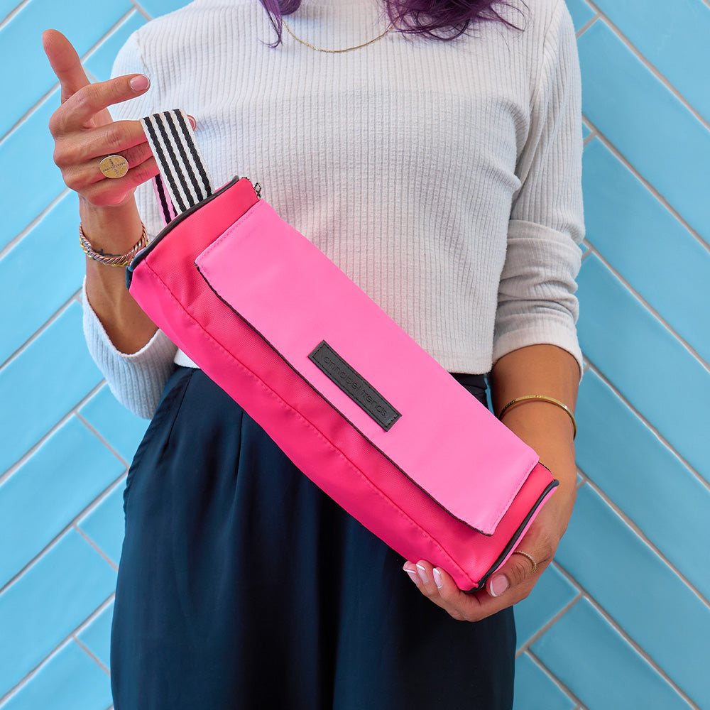Person holding a pink hair straightener bag against a blue tiled wall