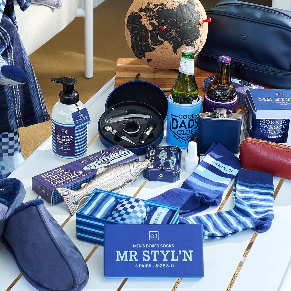 Collection of men's accessories and gifts including socks, slippers, and bottles on a table.