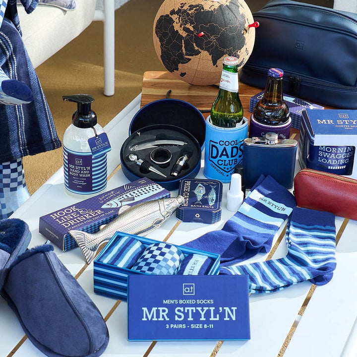 Collection of men's accessories and gifts including socks, slippers, and bottles on a table.