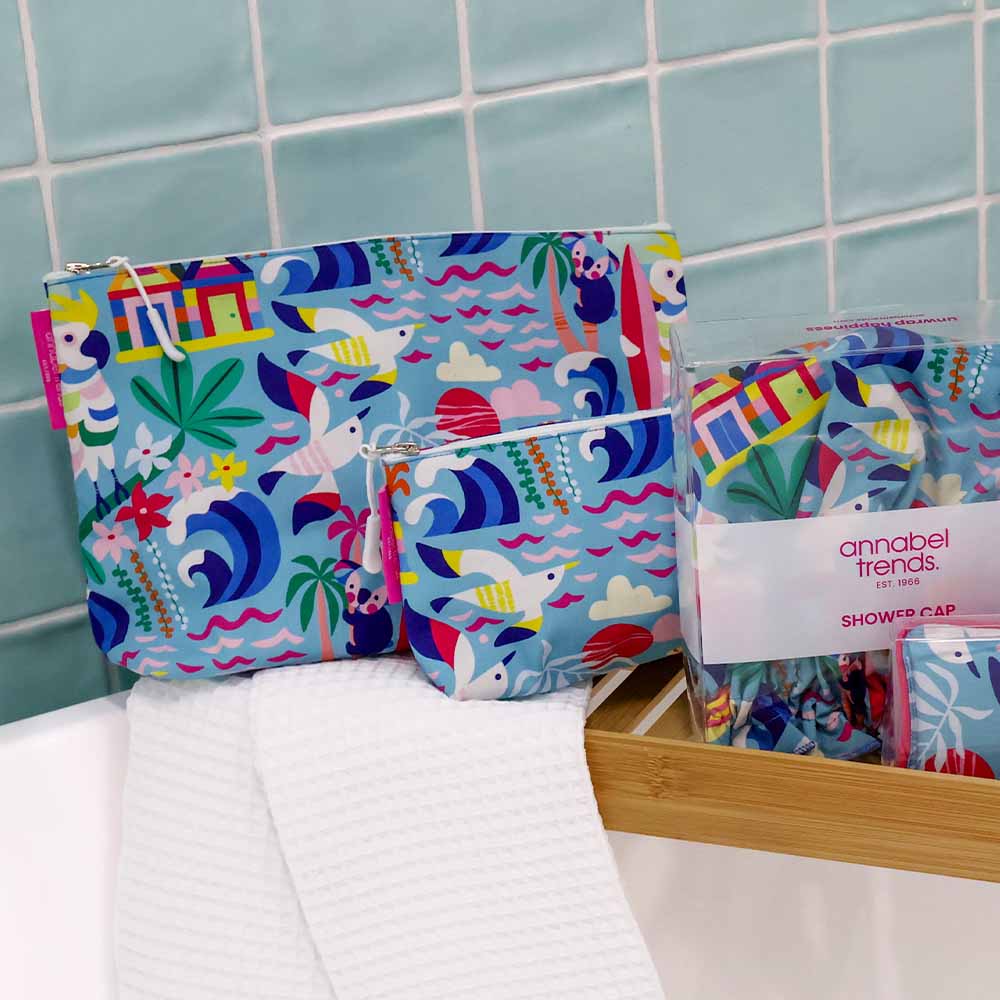 Colorful beach-themed pouches and shower cap on a tiled bathroom counter.