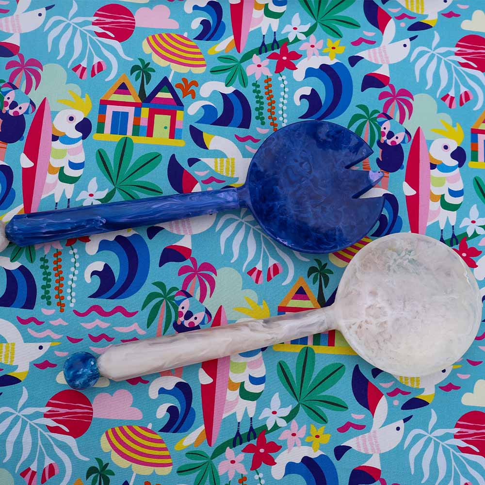 Two spoons on a colorful patterned fabric with tropical designs.