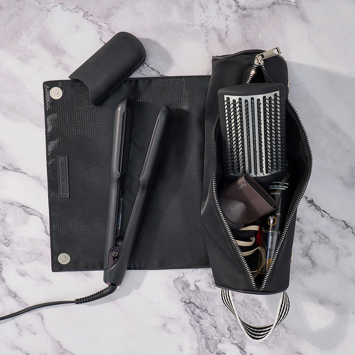 Black hair straightener and grooming kit on a marble surface