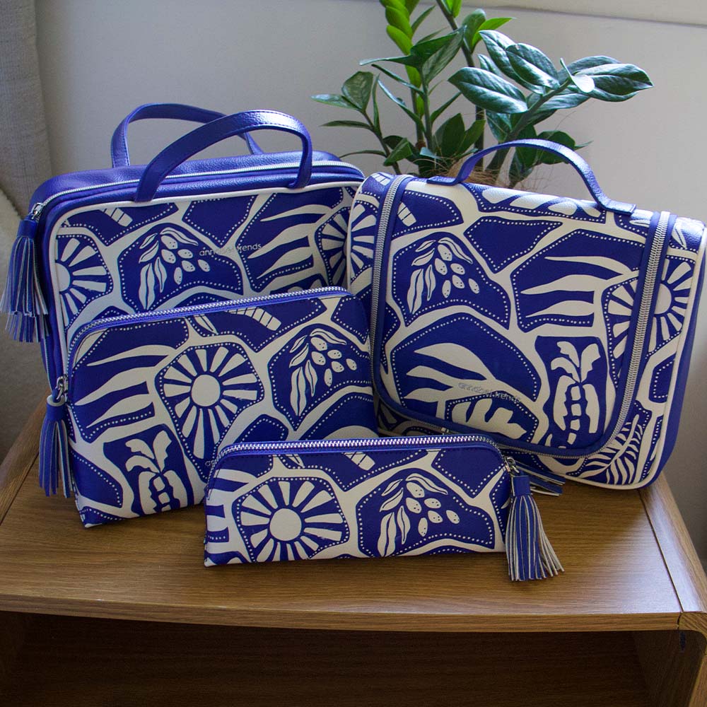 Set of blue and white patterned bags on a wooden surface with a plant in the background