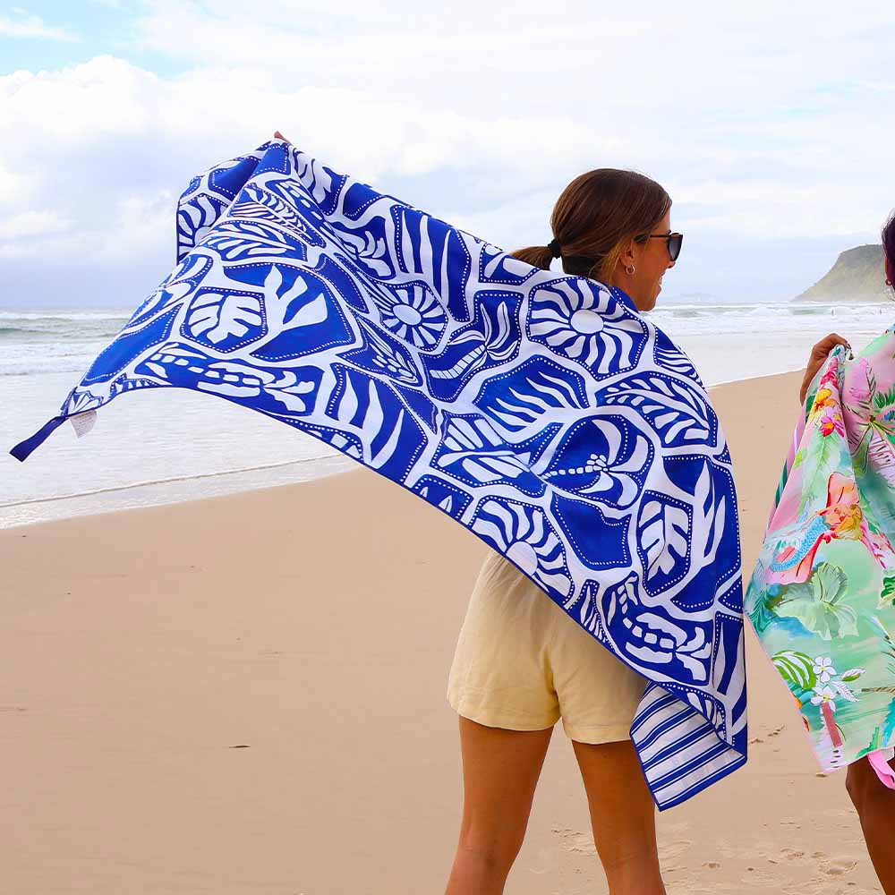 Person on a beach holding a blue and white patterned towel