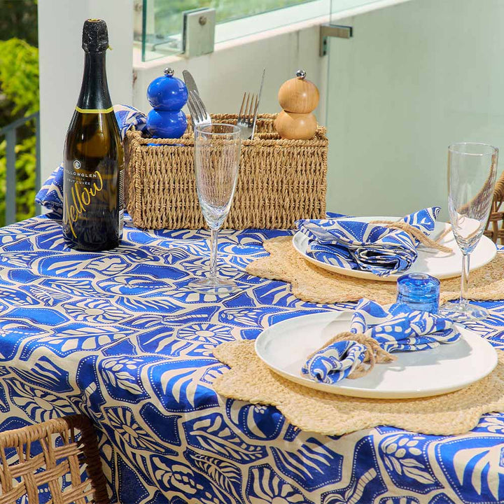 Table setting with blue and white patterned tablecloth, wine bottle, and glasses.