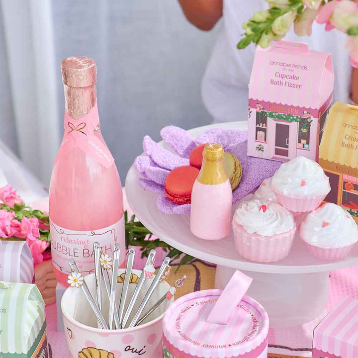 Pink bottle, bath bombs, and other items on a table with a blurred background